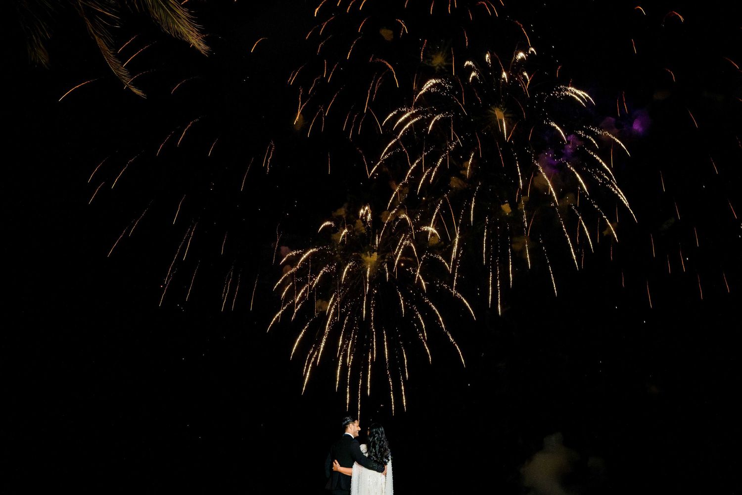 Bright golden fireworks exploding against a dark night sky with sparkling trails of light.