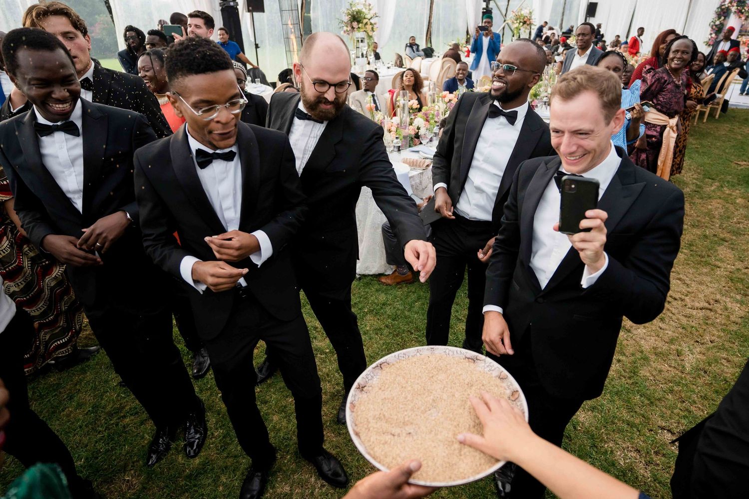 Wedding guests gather outdoors in formal attire for a celebratory moment during a reception.