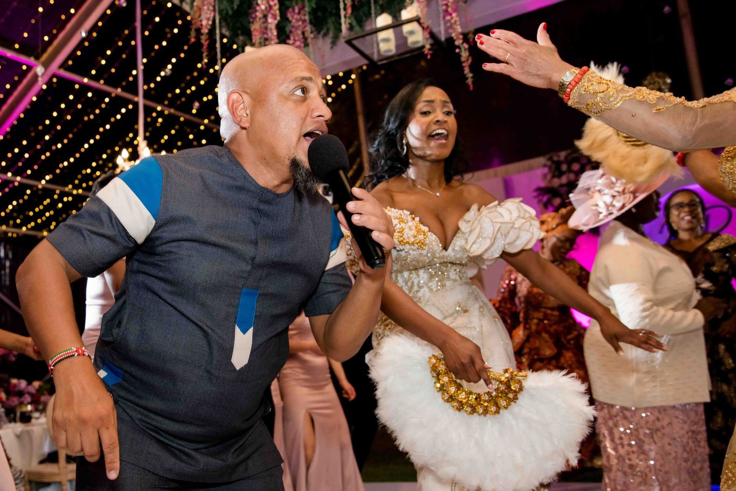 Energetic dance party at a wedding reception with guests celebrating under string lights.