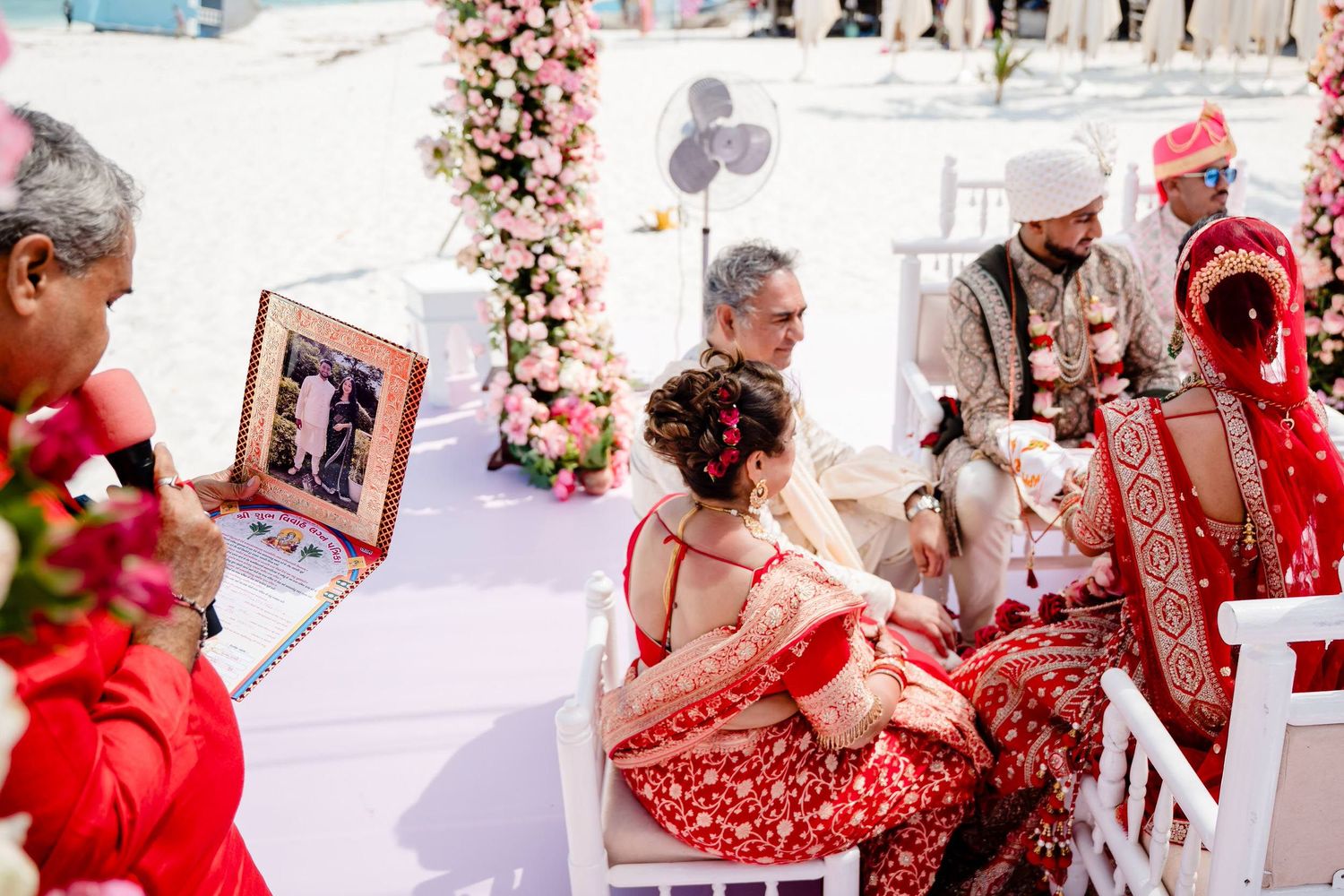 Traditional Indian wedding ceremony with red and white decor featuring floral arrangements and cultural attire.