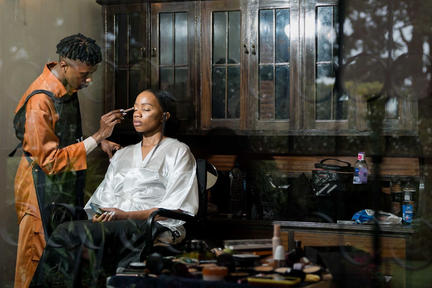 Two people work together in a dimly lit workshop space with tools and equipment visible in the background.