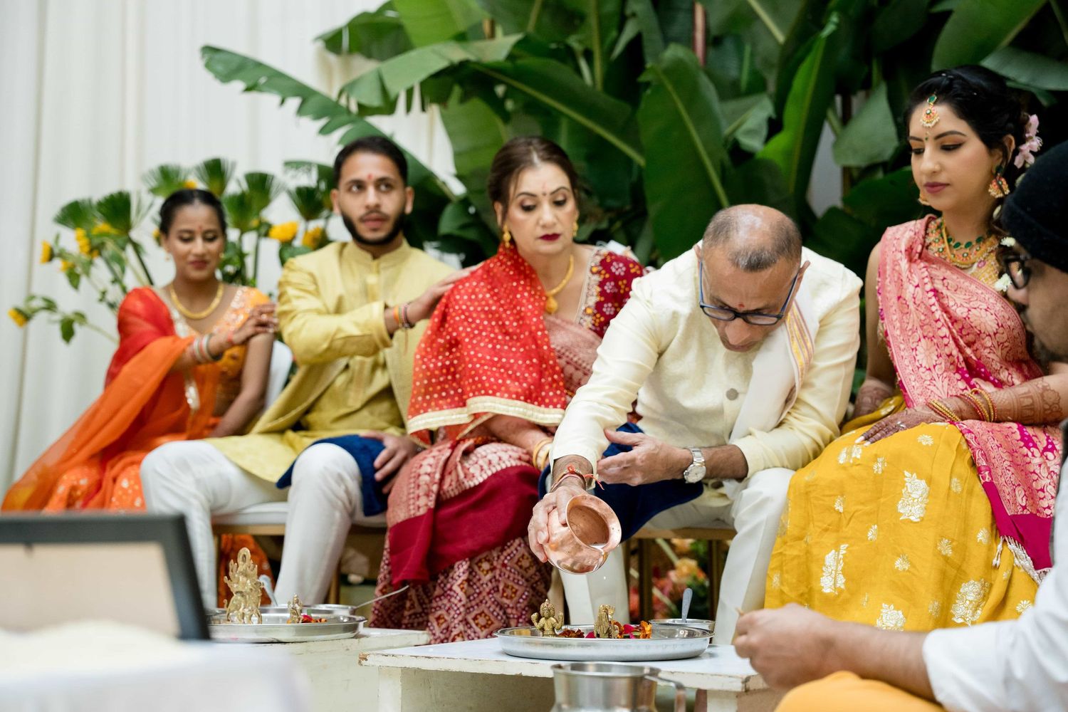 Family members participating in traditional Indian ceremony with colorful attire and decorations.