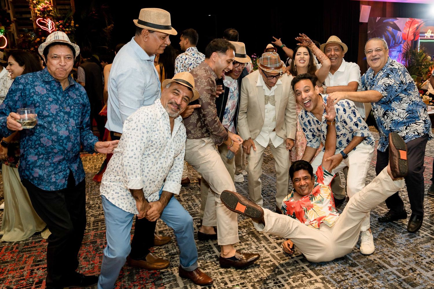 A fun group of party goers in casual attire dance and pose together during a festive celebration.