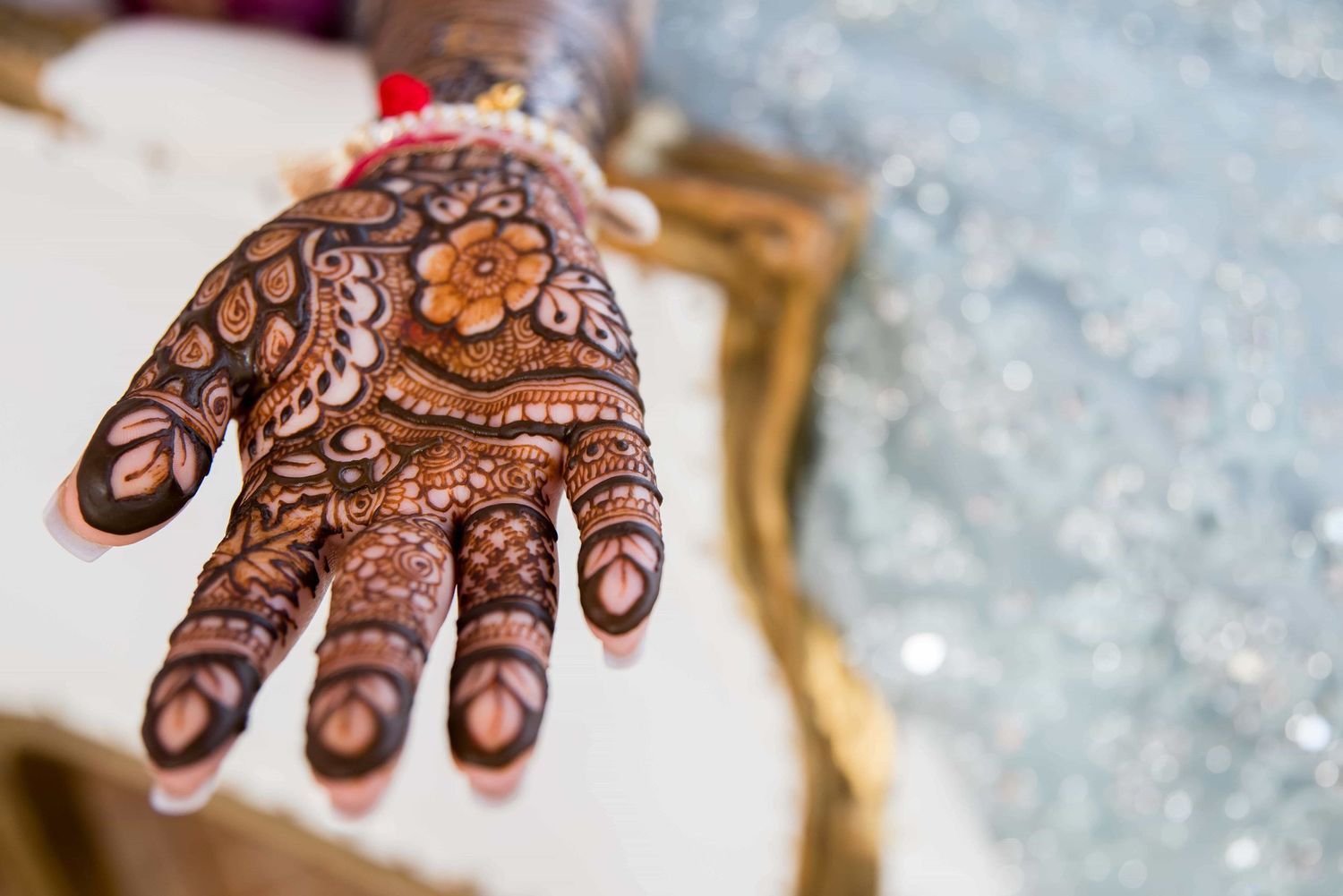 Detailed view of traditional henna mehndi design on palm against blurred background.
