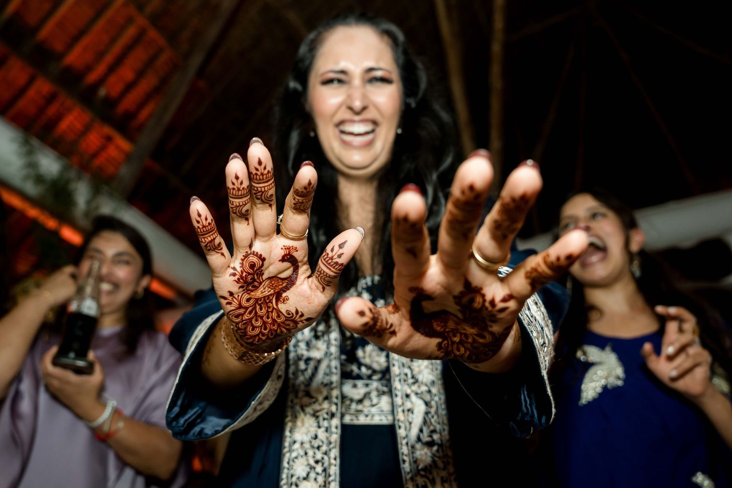 Group of people showing off intricate henna designs on their hands at a celebration.