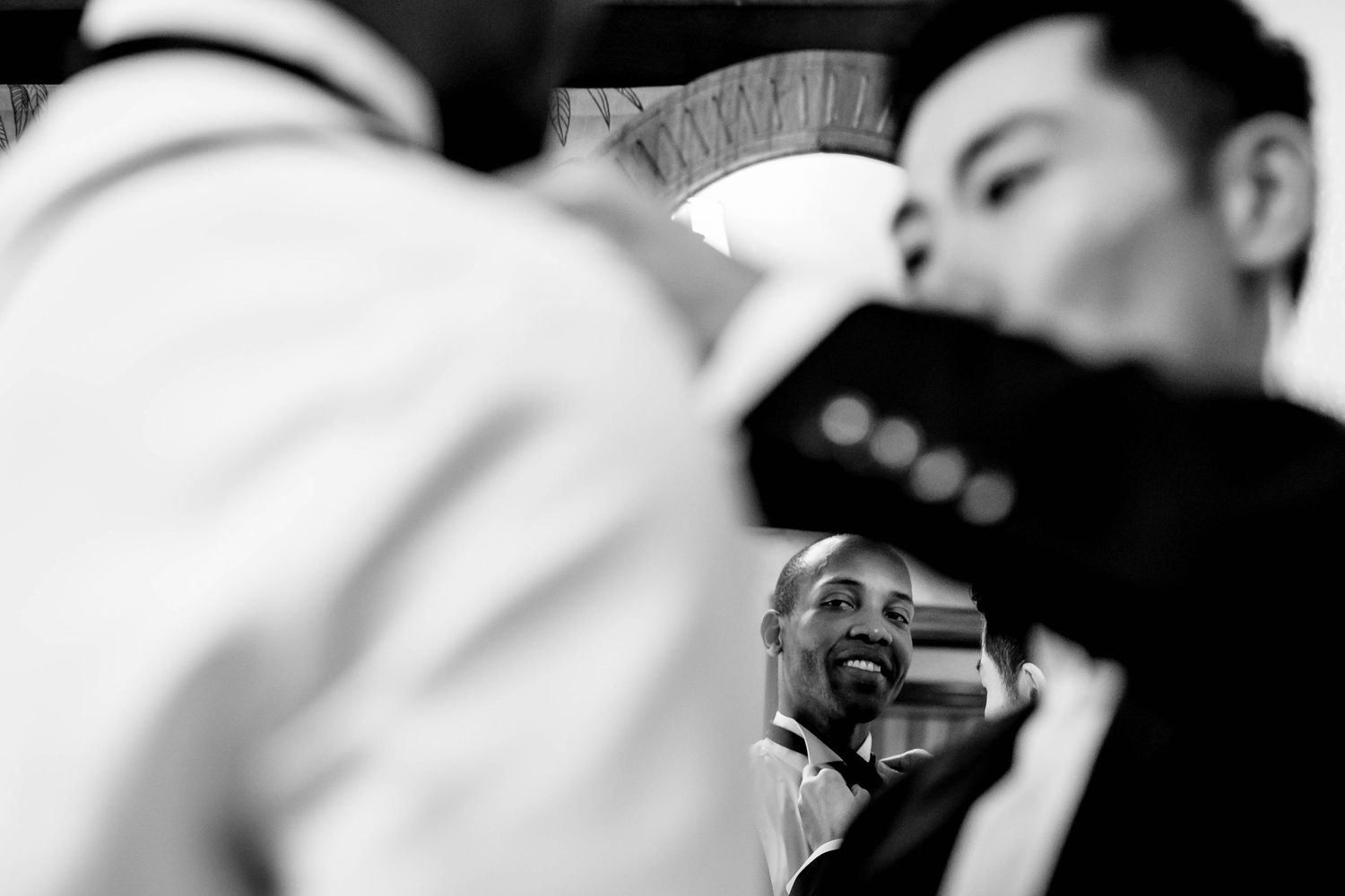 Black and white candid photo capturing joyful laughter through a mirror reflection.