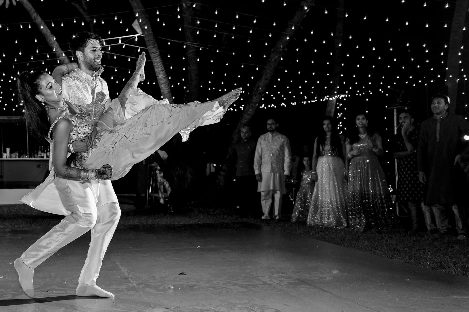 A black and white photo captures a dramatic dance lift during a reception.