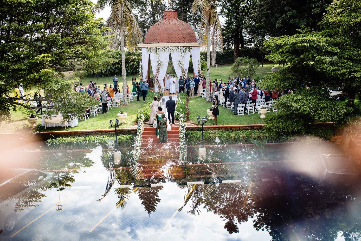 Garden wedding ceremony at gazebo with reflection in water feature.