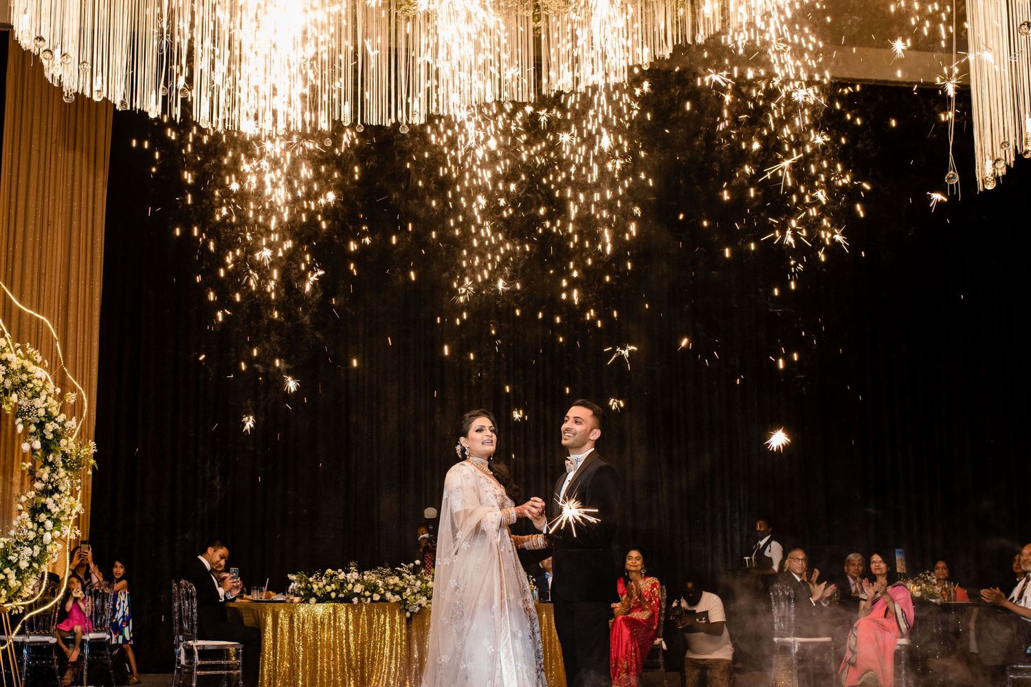 Wedding celebration under sparkling gold curtains and twinkling lights.
