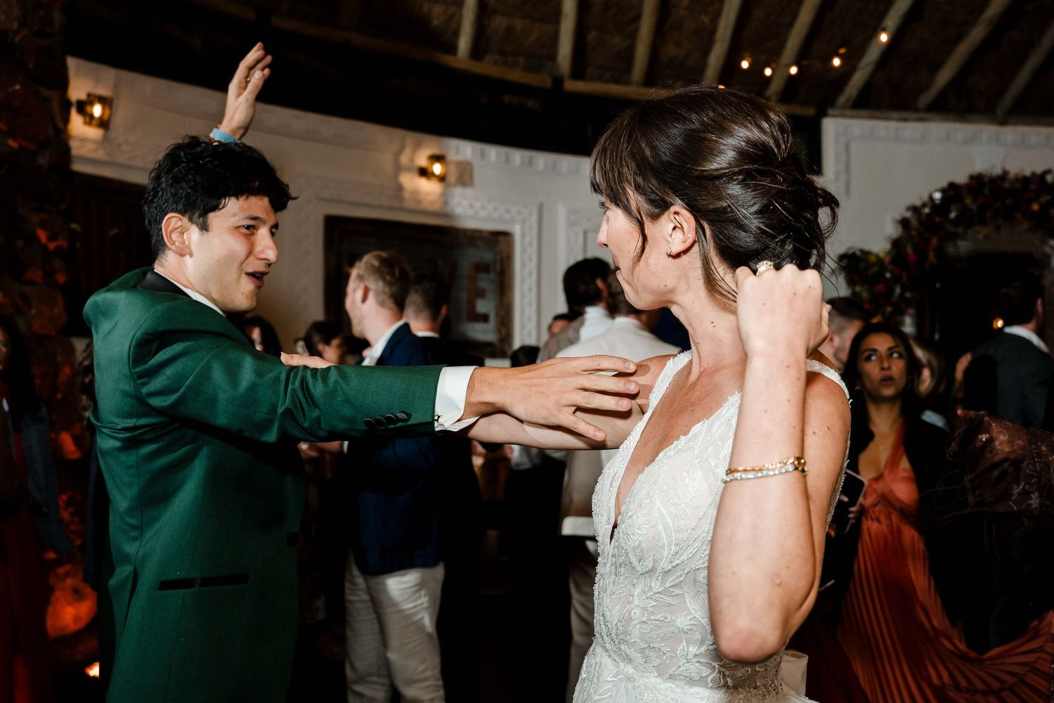 A couple dances together at a wedding reception while other guests watch in the background.