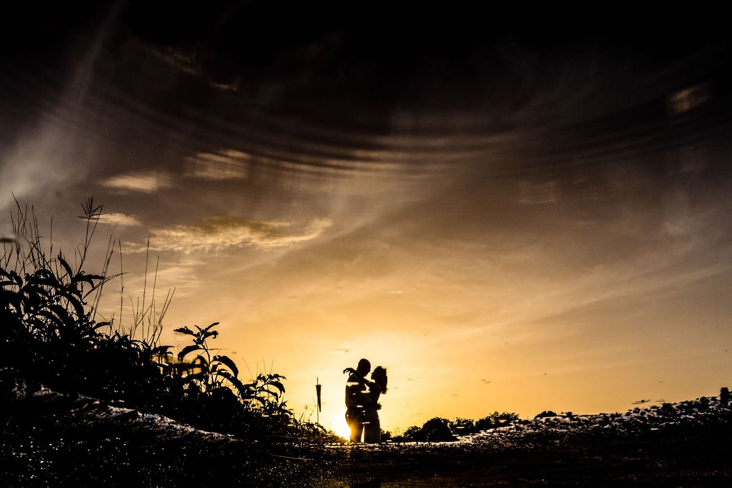 Dramatic sunset silhouettes create a romantic atmosphere in an outdoor setting.