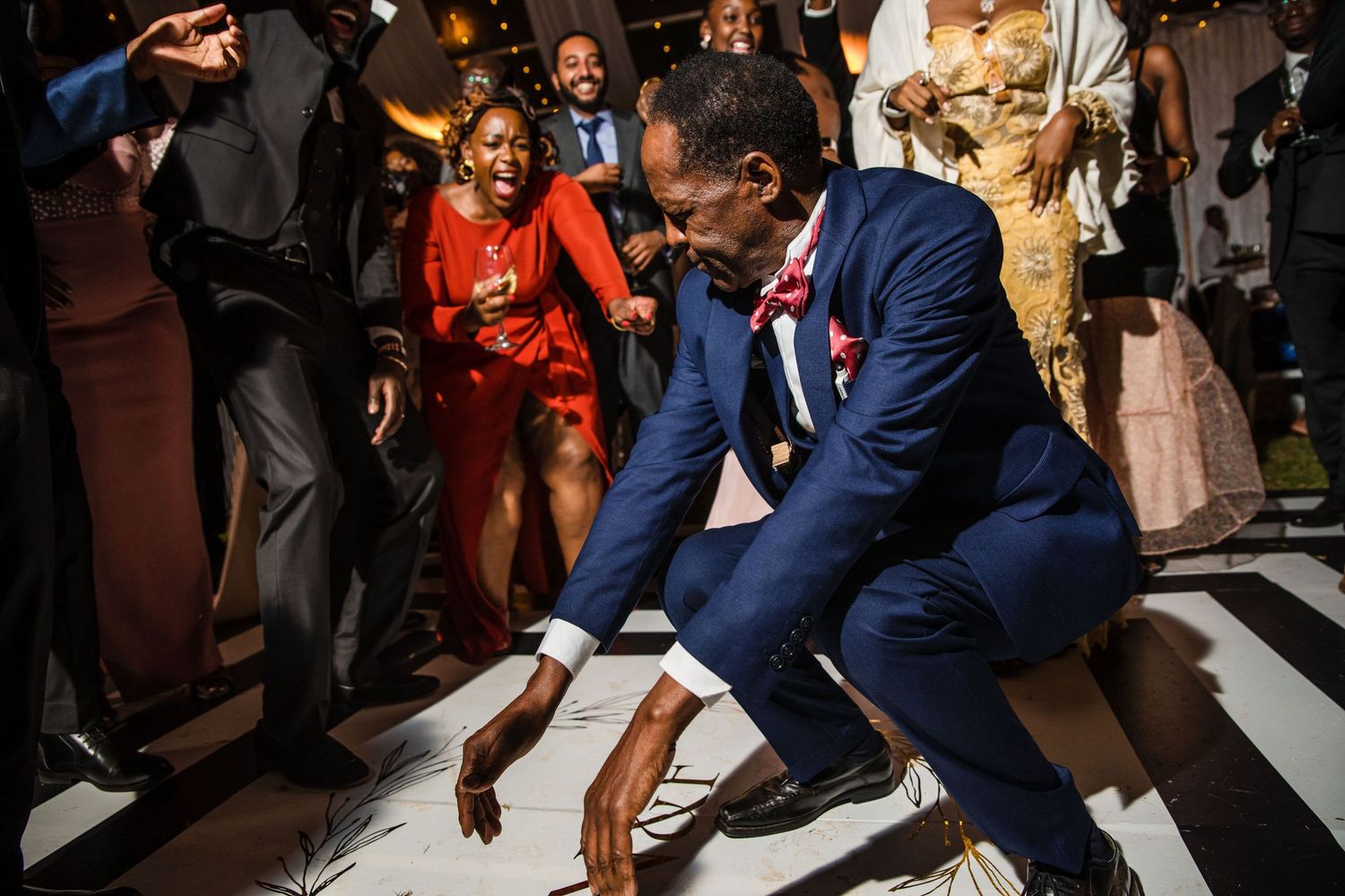 Wedding guests dancing energetically on a dark dance floor with dramatic lighting.