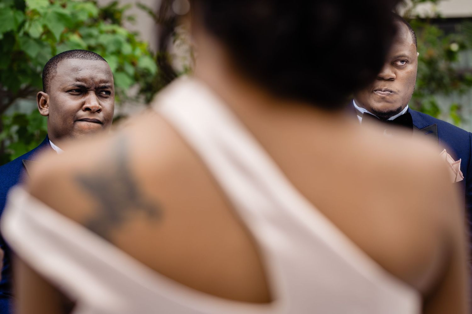 Close-up emotional moment during wedding ceremony showing shoulder tattoo detail.