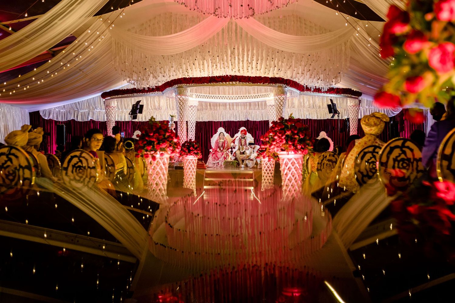 Elegant wedding venue decorated with pink lighting and crystal chandeliers.