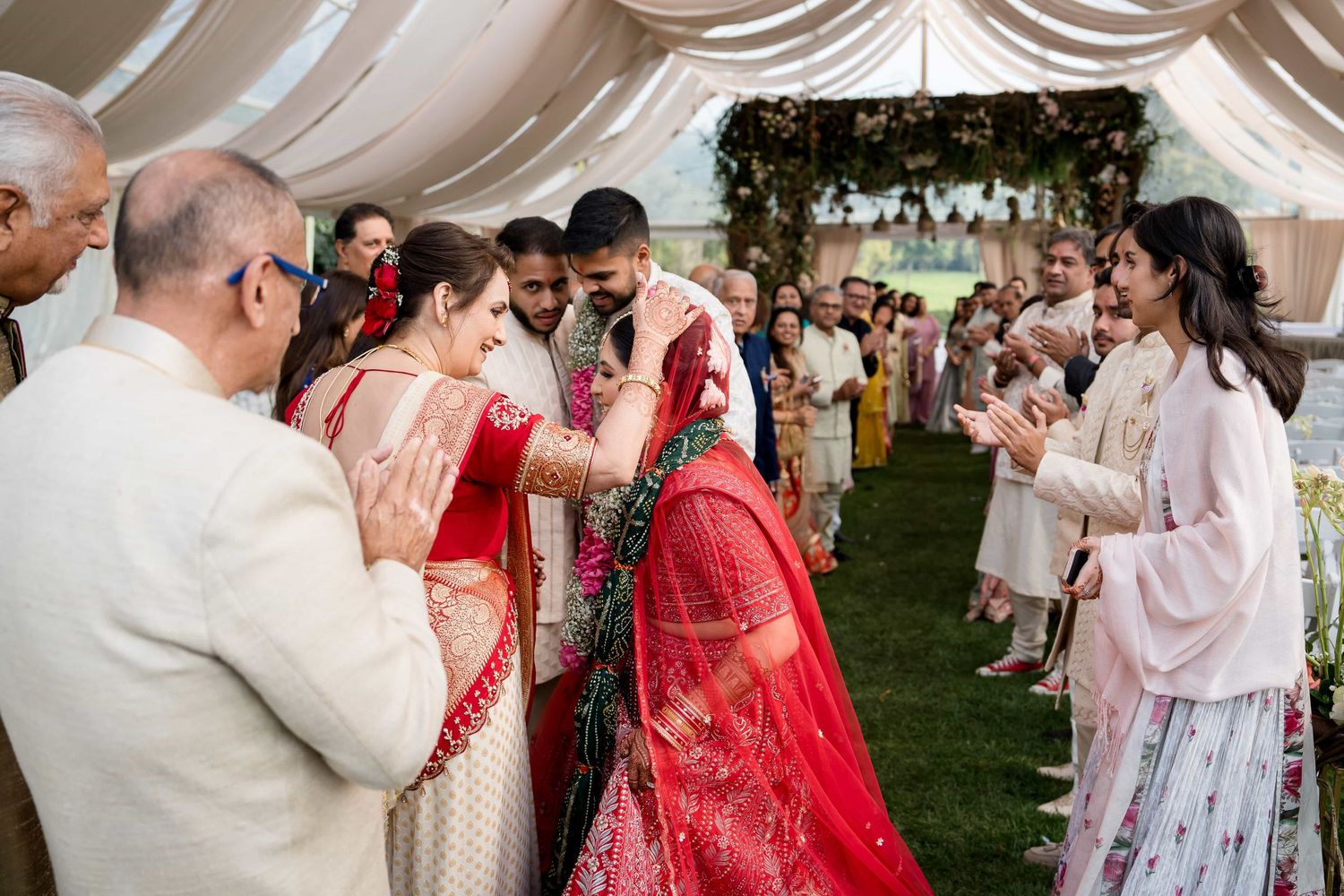 Joyous cultural wedding ceremony taking place under an elegant white draped tent with guests looking on.
