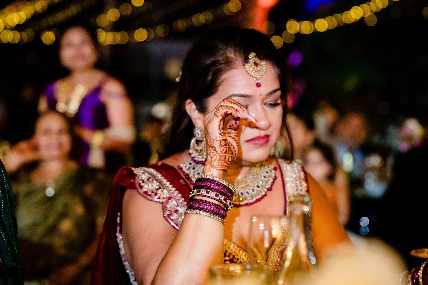 Joyous celebration at an Indian wedding with colorful decorations and festive lighting in the background.