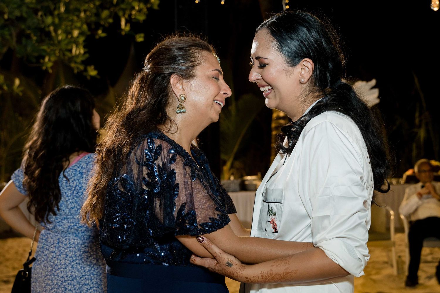 Two people share a joyful dance moment on a wooden floor during what appears to be a celebration.