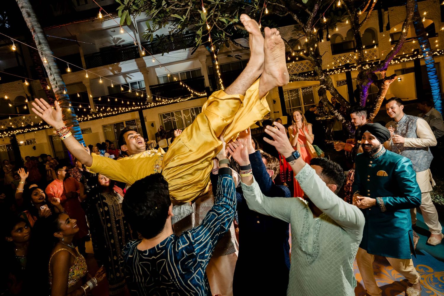 Energetic celebration with guests lifting someone during a festive dance party.
