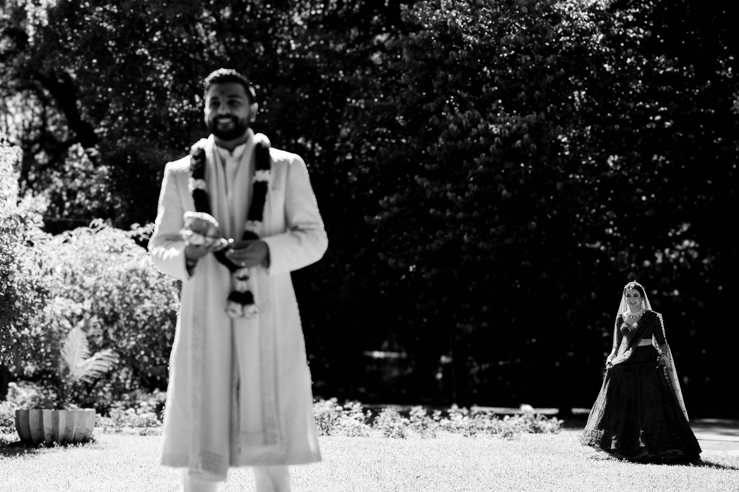 Black and white photo of a traditional ceremony in an outdoor garden setting.