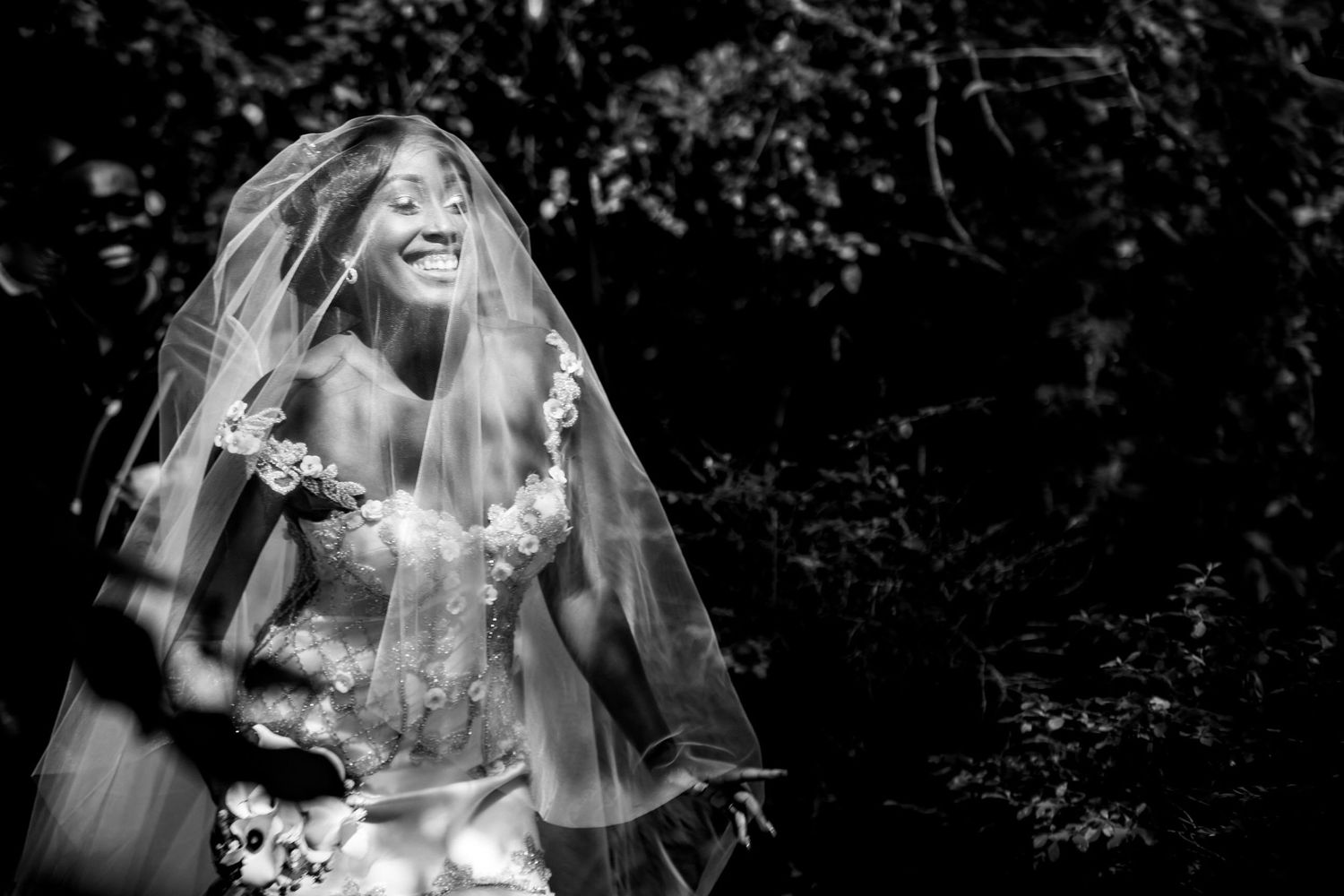 Candid black and white photo of a bride in her wedding dress outdoors with natural lighting.