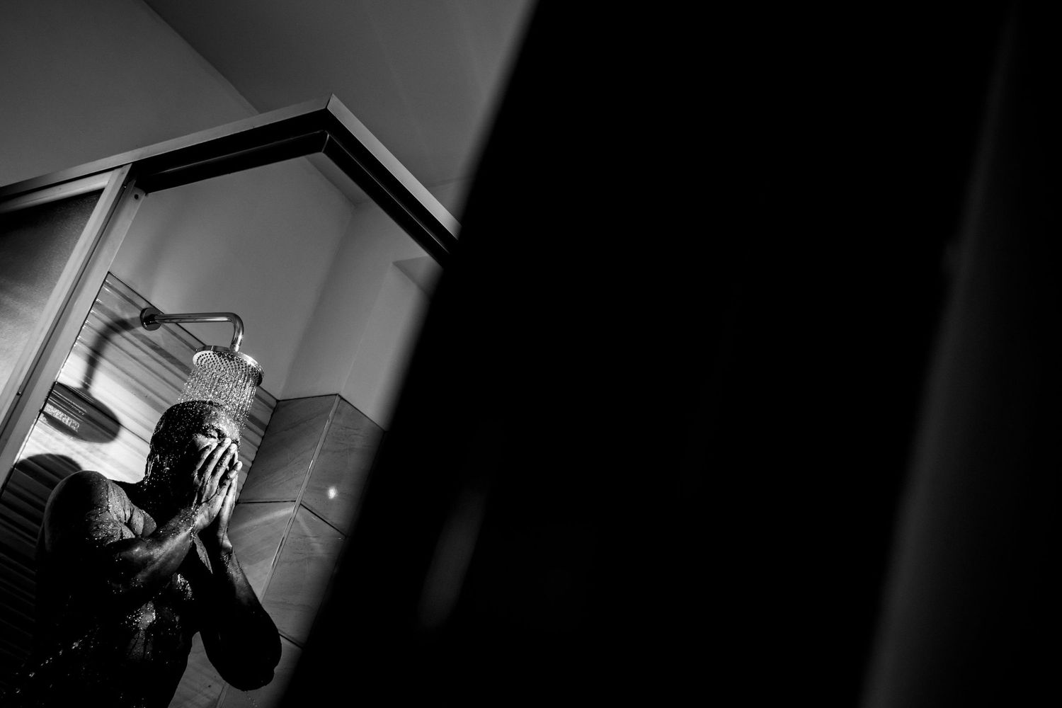 A dramatic black and white silhouette of someone drinking from a cup in a corner.