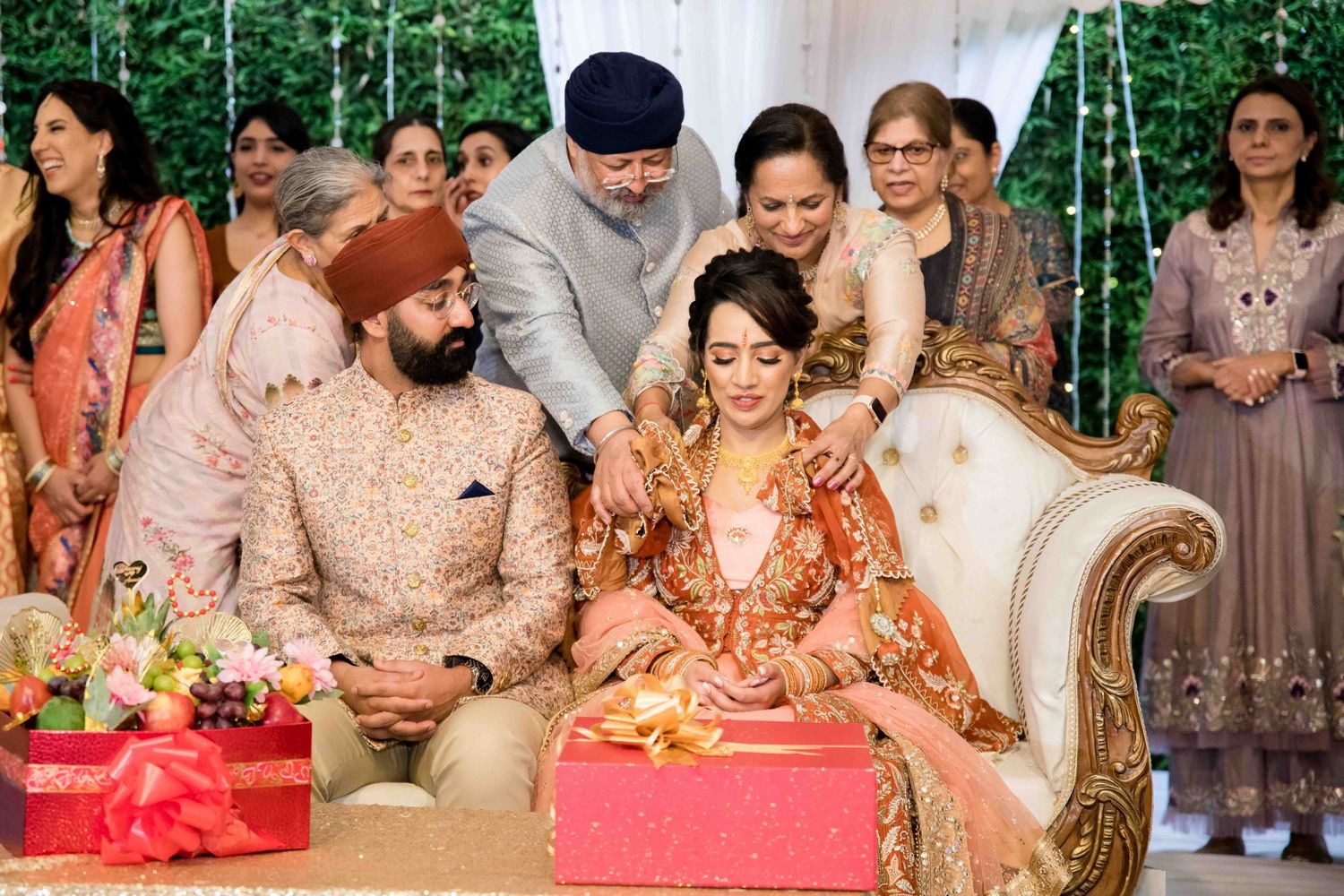 A traditional Sikh wedding ceremony with guests gathered around a decorated seating area.