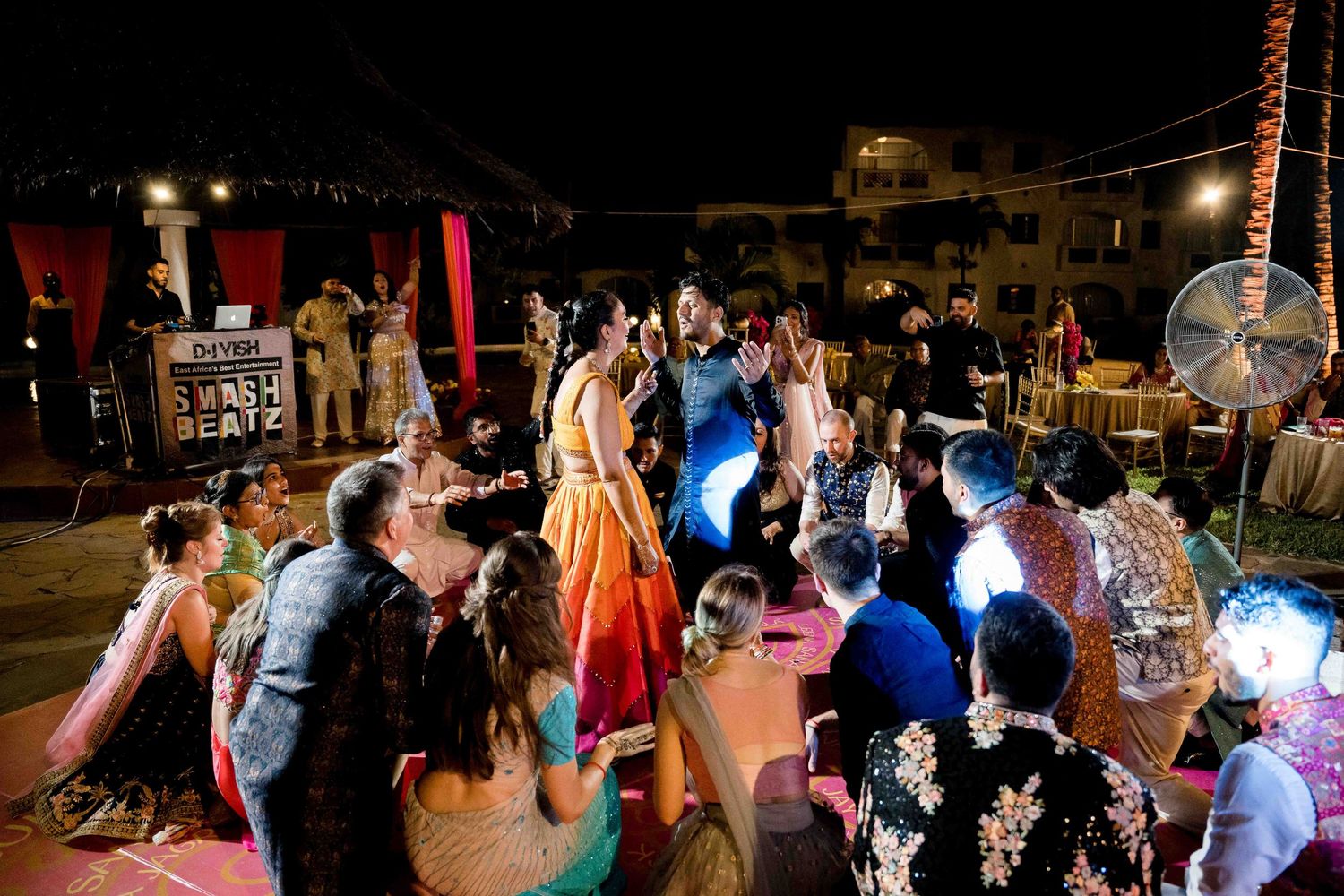 Wedding guests fill a dance floor under ambient lighting during an evening celebration.