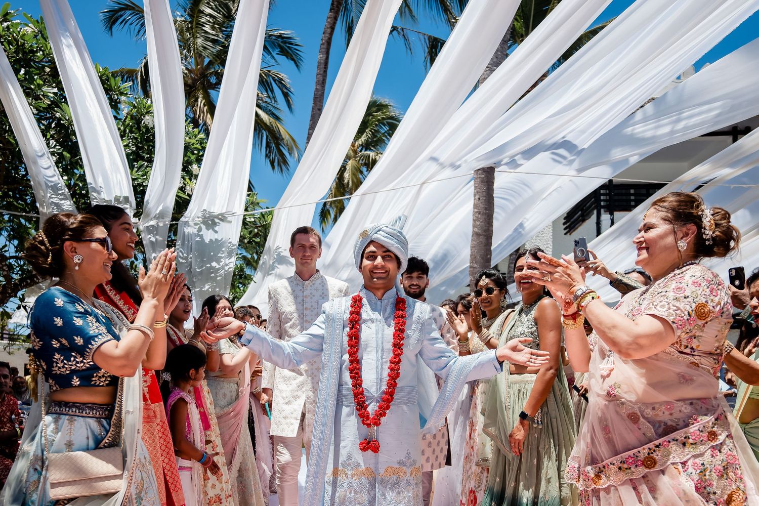Wedding celebration under white draped canopy with guests dancing and celebrating.