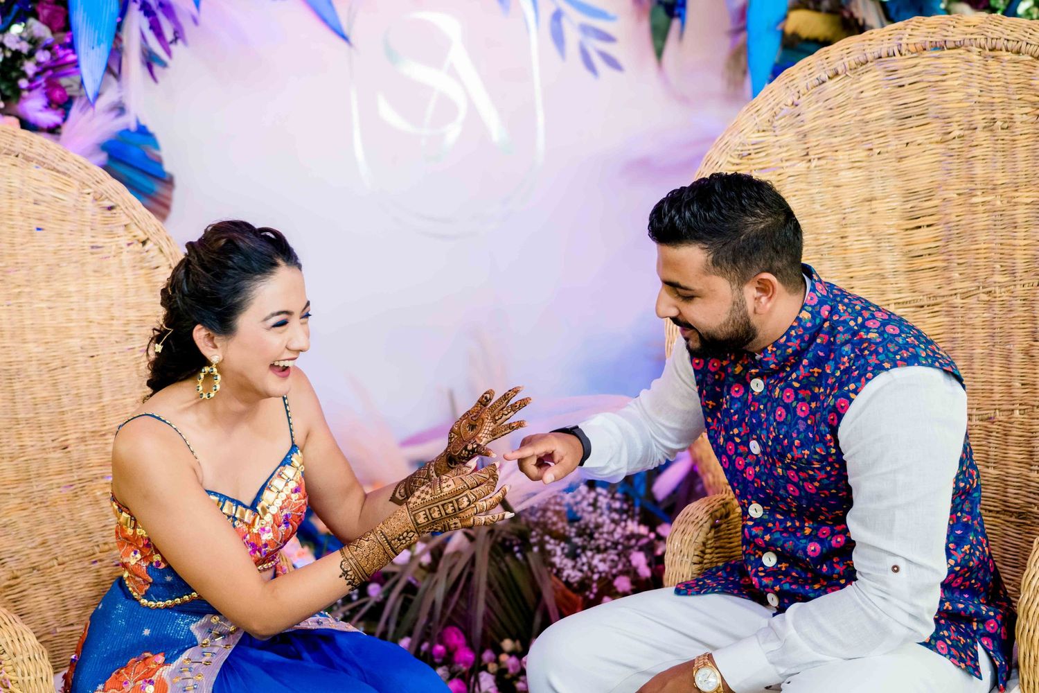 Couple sharing a joyful moment together on ornate wicker chairs during a celebration.