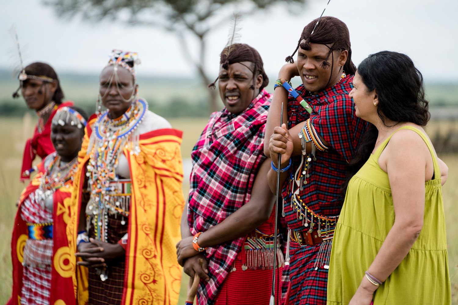 Group in traditional African attire and colorful garments gather at outdoor celebration.