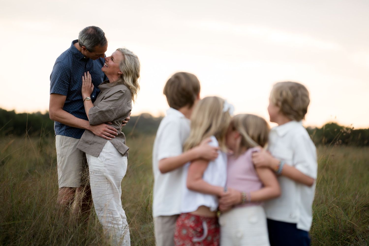 A loving family embraces in a sun-drenched meadow during golden hour.