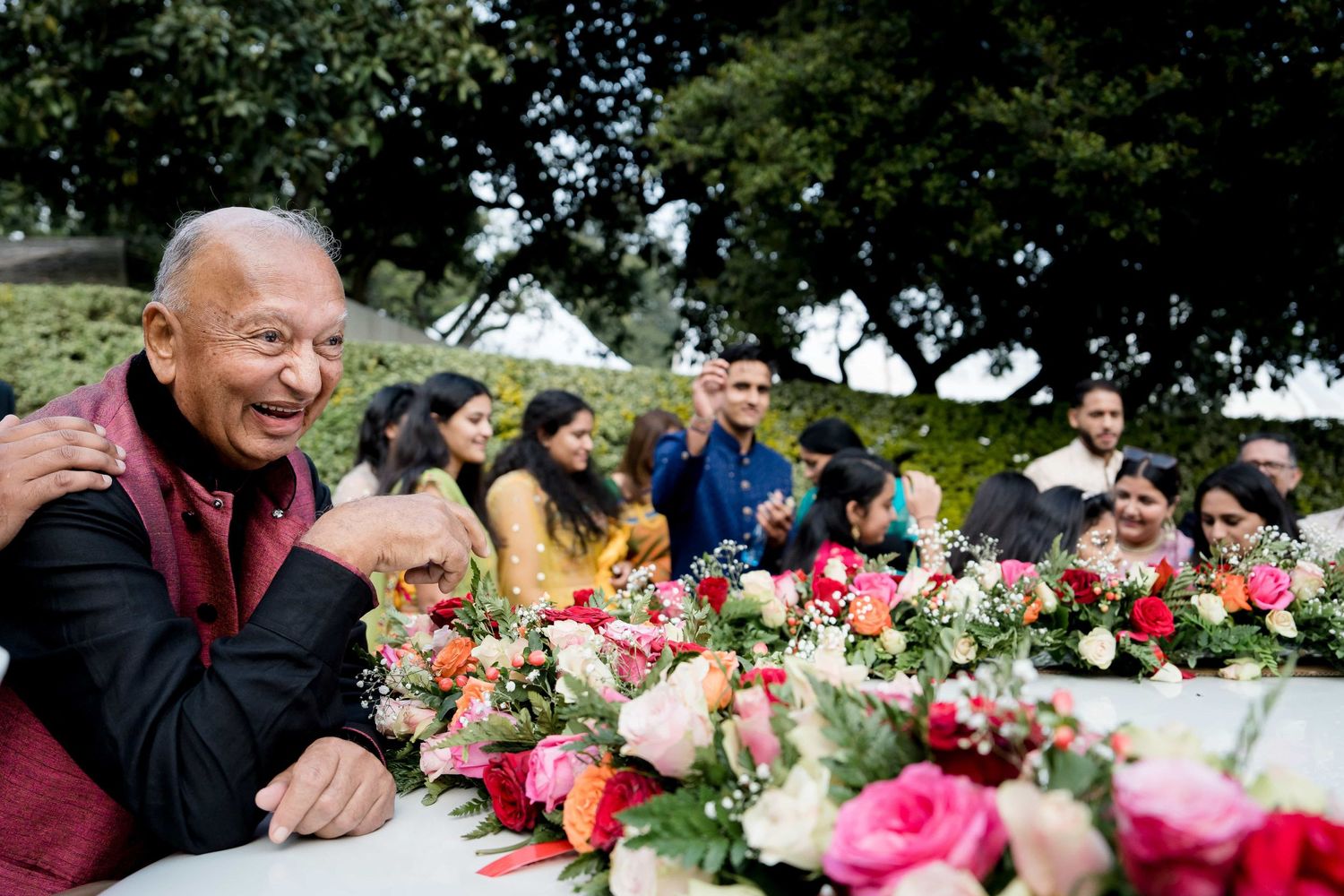 Wedding reception table adorned with pink floral arrangements and smiling guests.