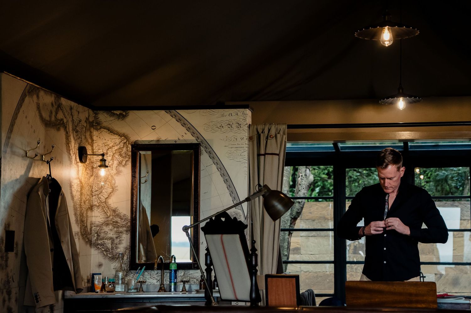 Person in formal attire preparing in rustic room with vintage decor and natural lighting.