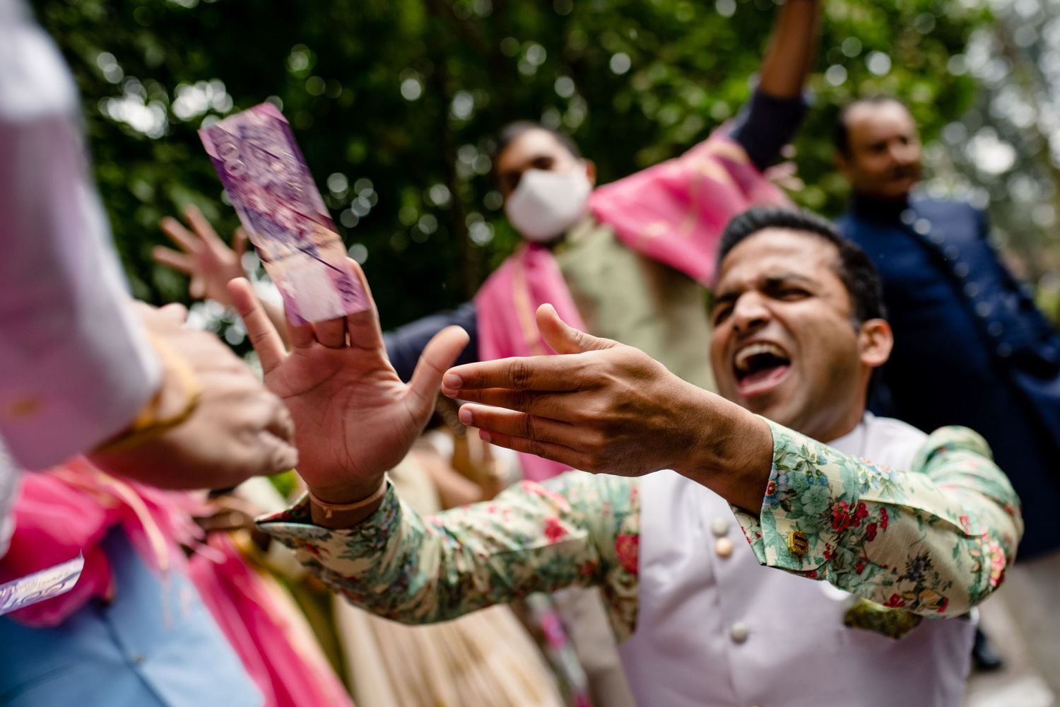 Celebratory moment with hands reaching for pink money during festivities.