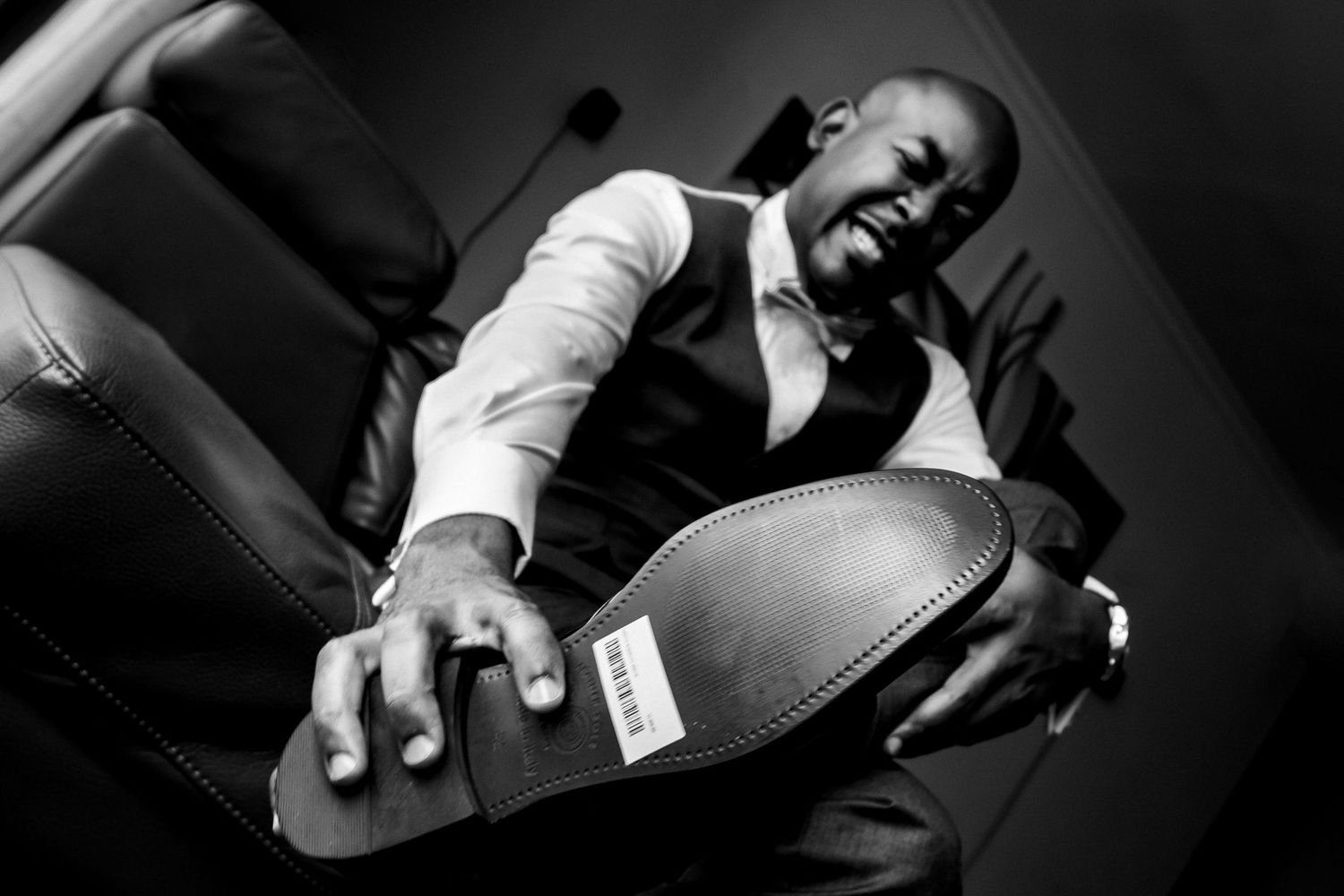 Dramatic black and white photo of someone holding a formal dress shoe.