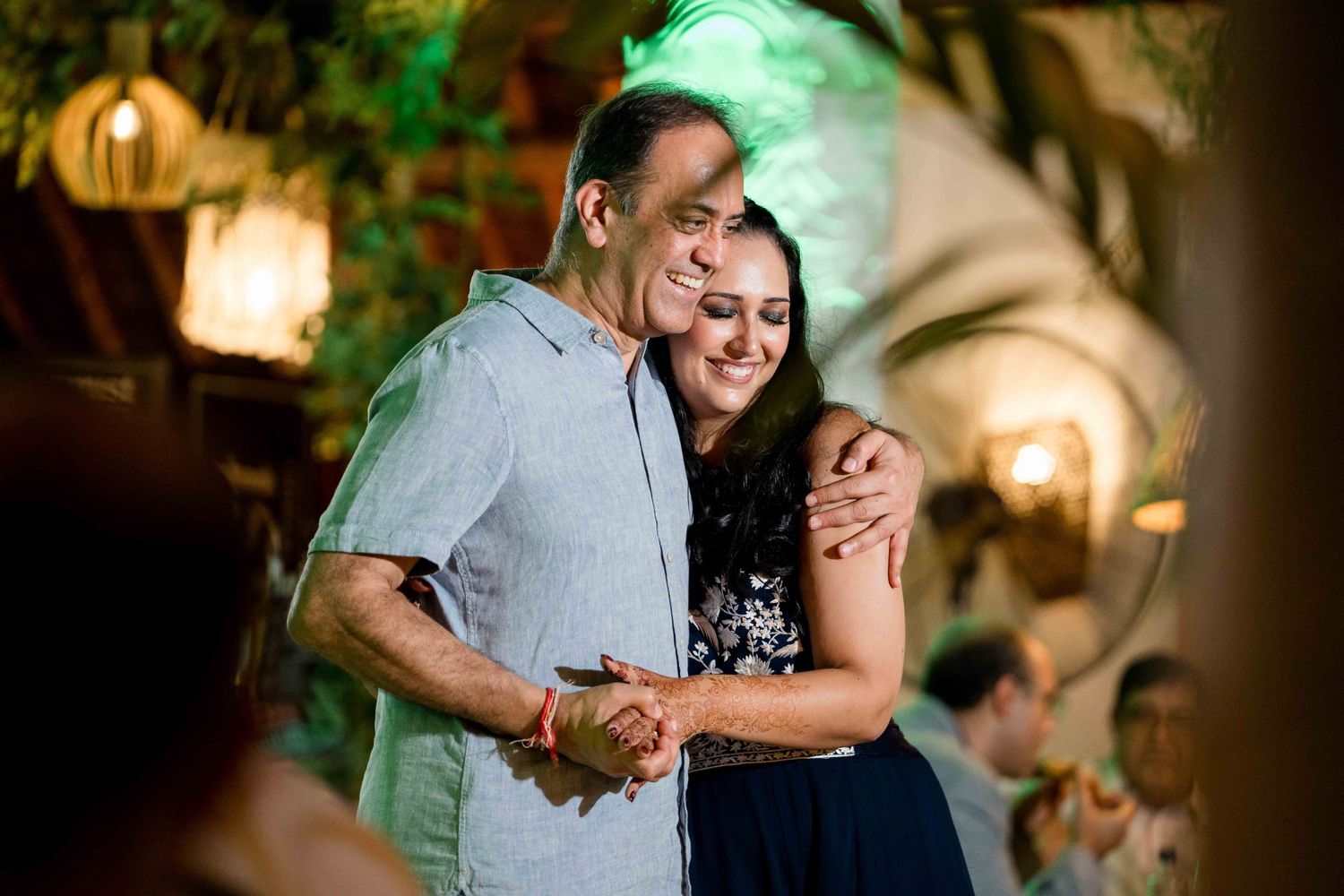 A couple embraces and laughs together during an intimate moment at a warmly lit venue.