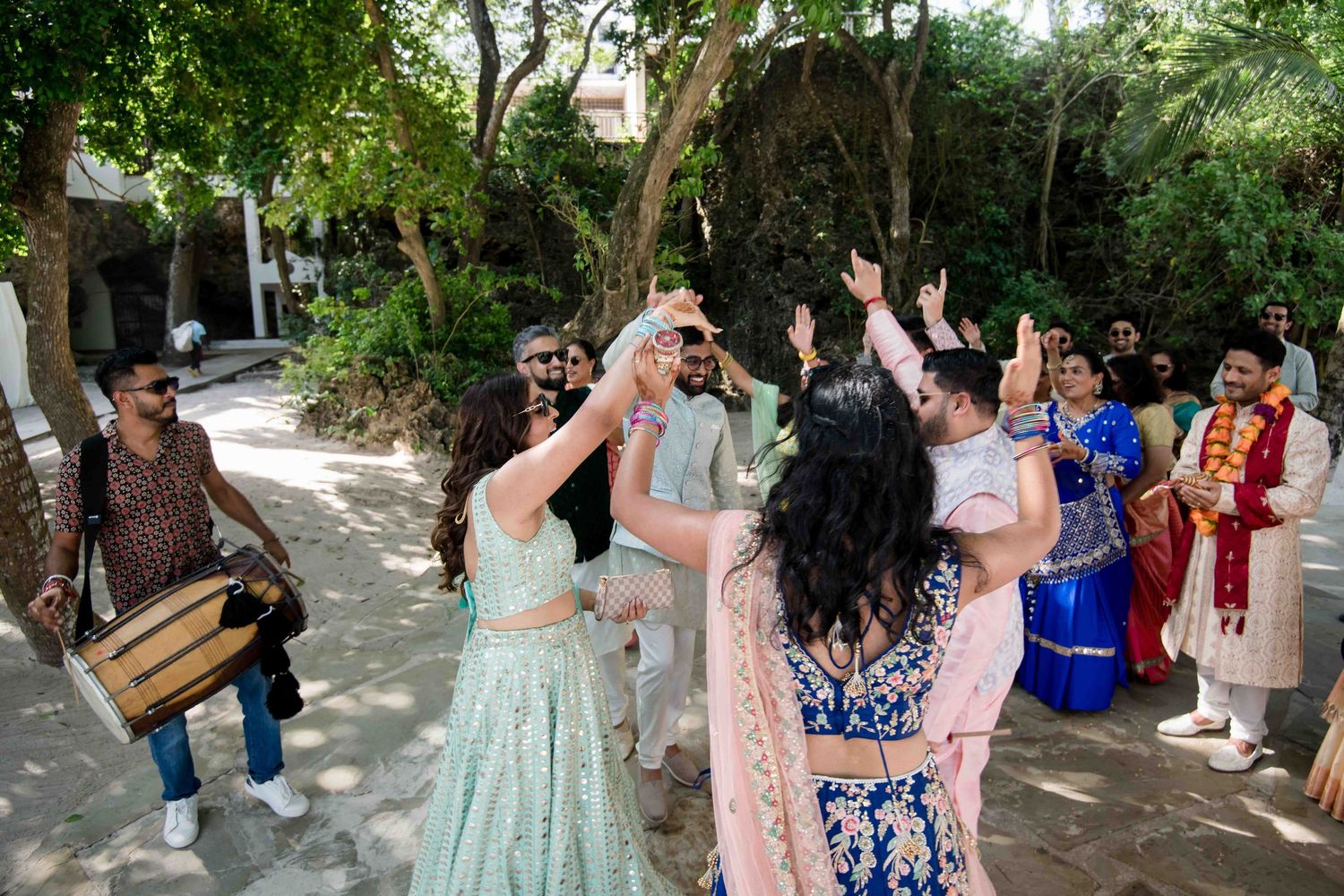A group of wedding guests form a receiving line outdoors in a garden setting to celebrate the newlyweds.