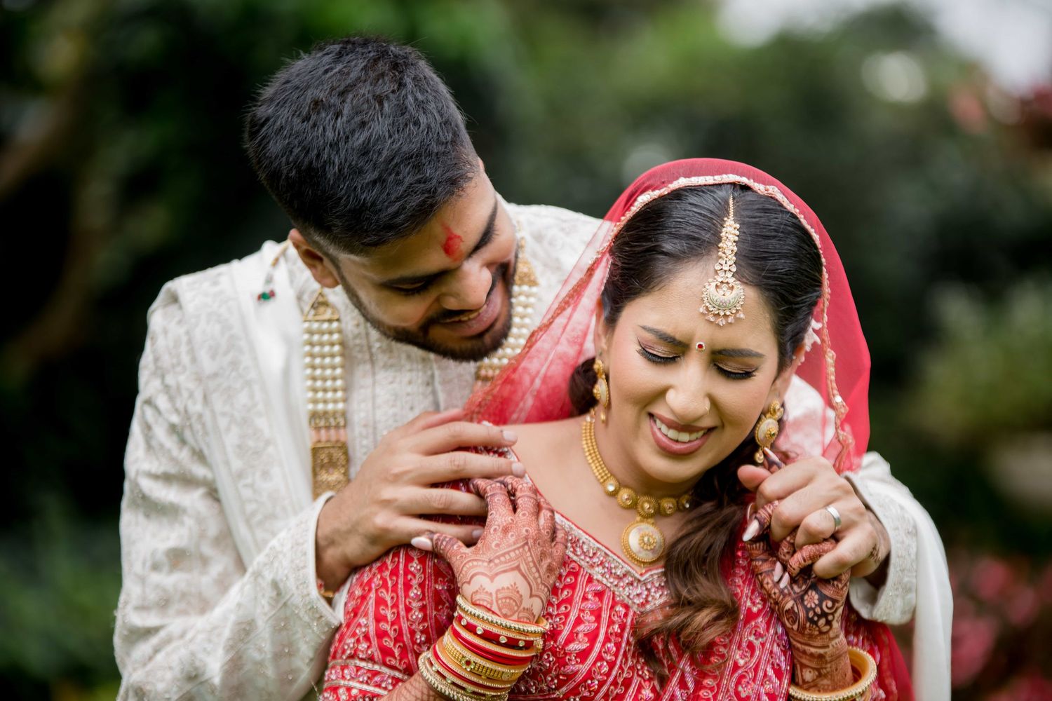 Candid moment of a couple in traditional Indian wedding attire sharing laughter.