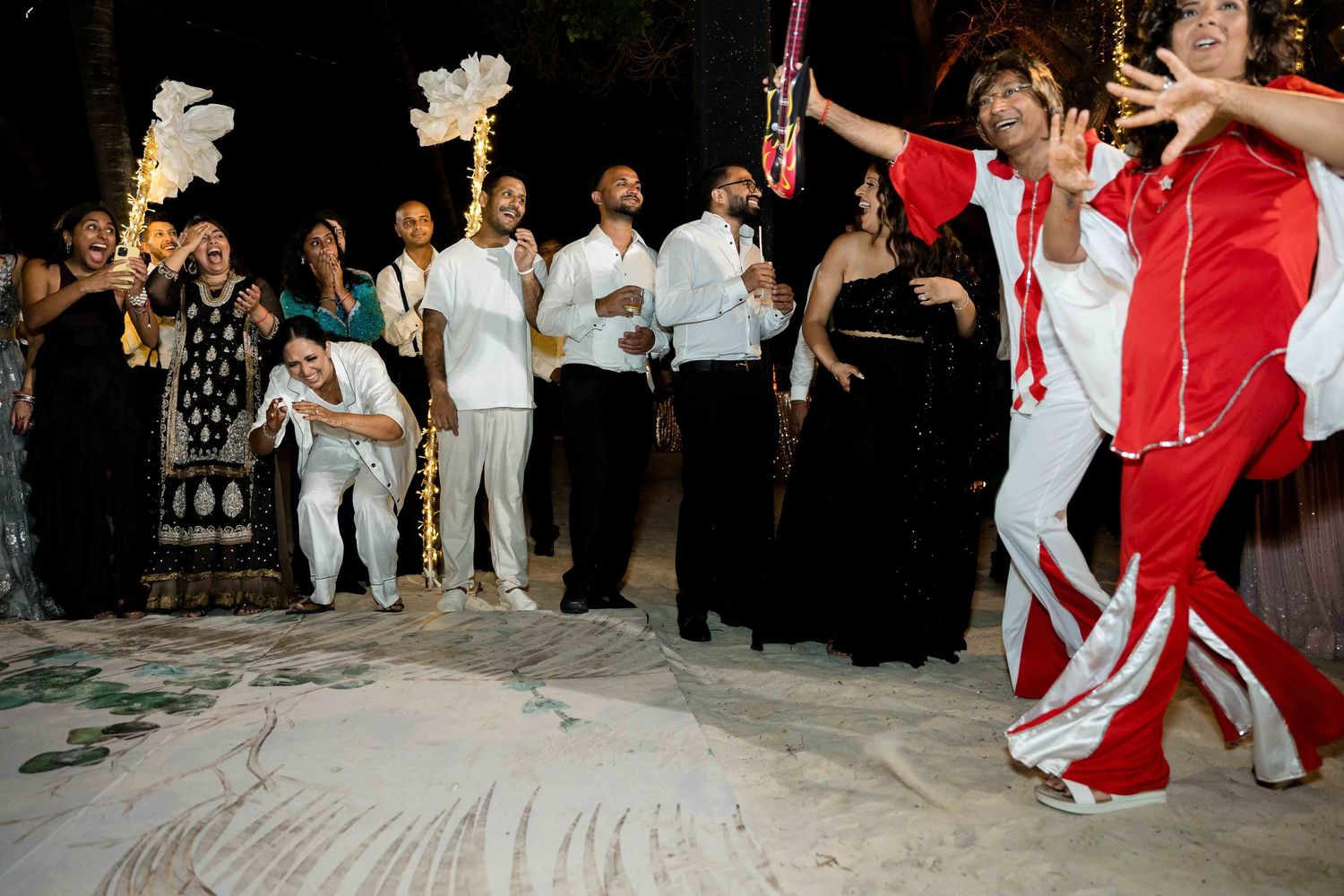 A group of dancers perform traditional Spanish flamenco moves in a line formation wearing red and white costumes.
