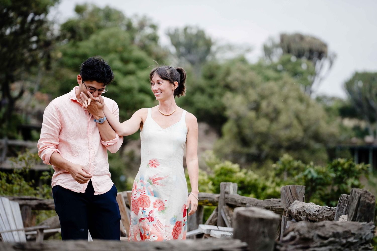 Two people share a joyful moment together in an outdoor garden setting with lush greenery in the background.