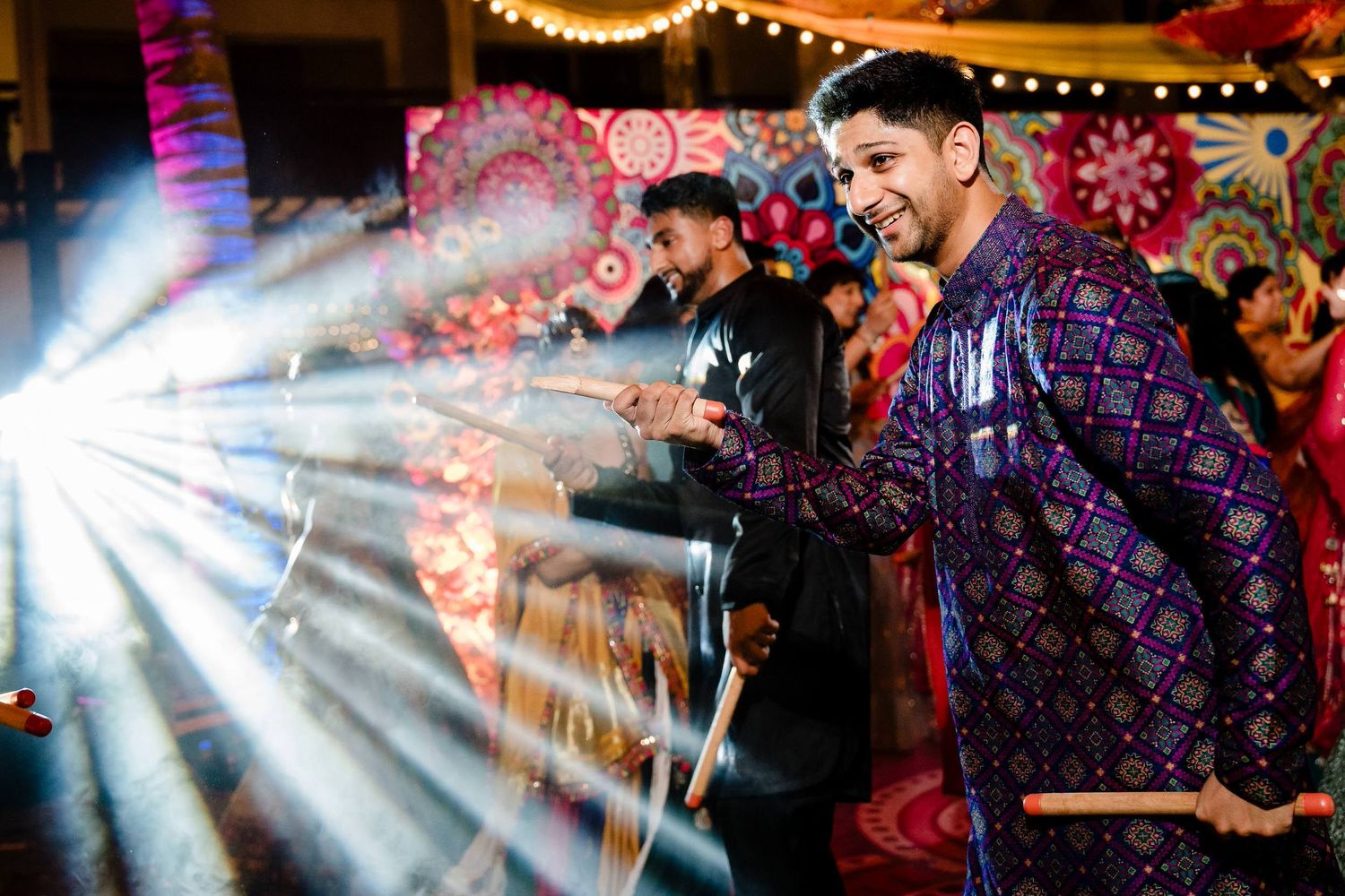 Concert crowd dances under colorful lights and decorations at a nighttime music festival.