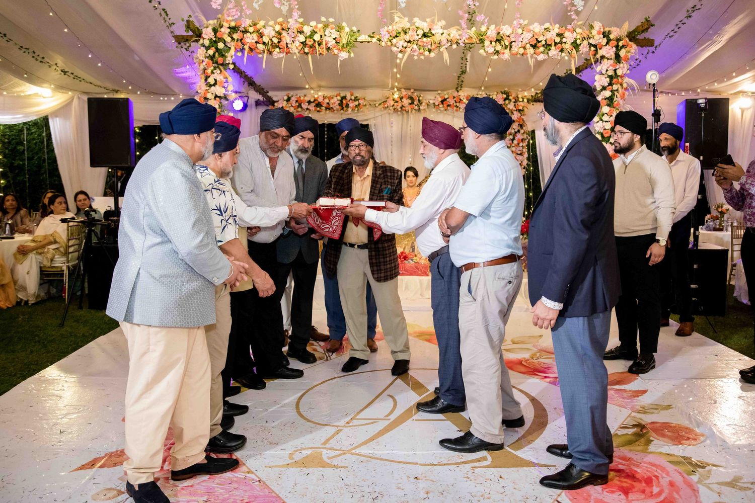 Wedding guests exchanging gifts during a reception under decorative lighting.