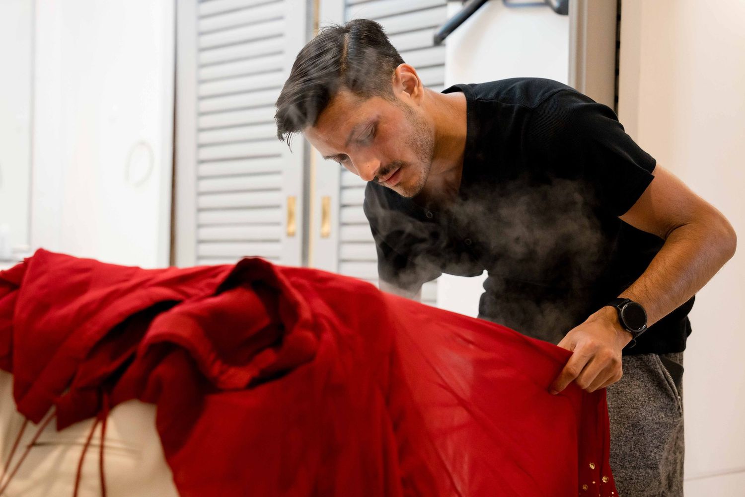 Steam rises as someone uses a massage tool on a red blanket covered surface.
