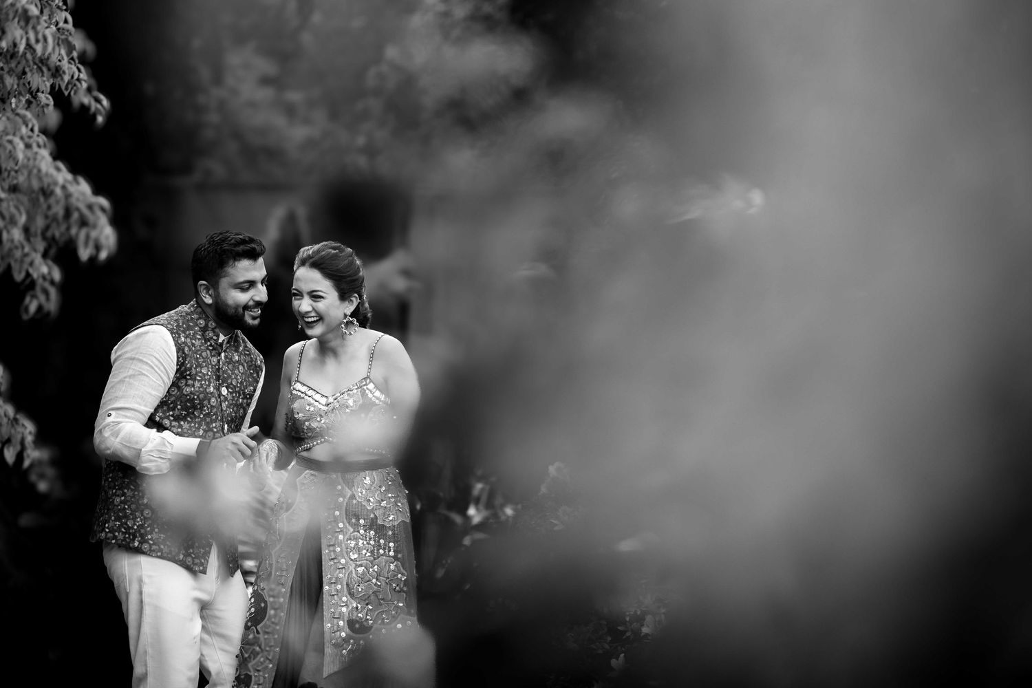 Artistic black and white portrait of a couple sharing an intimate moment outdoors.