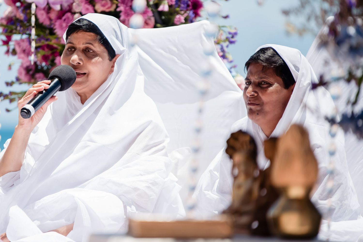 Spiritual ceremony with attendees in white robes seated outdoors.