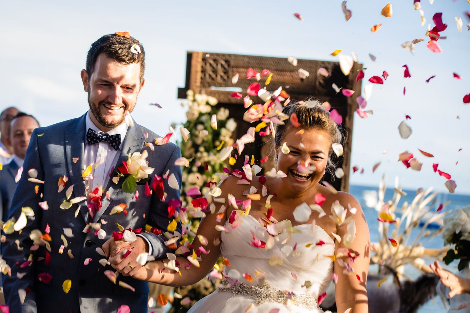 Rose petals and confetti float through the air during an outdoor celebration.