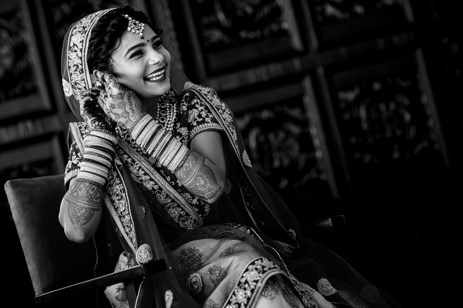 Black and white portrait of a bride in traditional Indian wedding attire laughing joyfully.