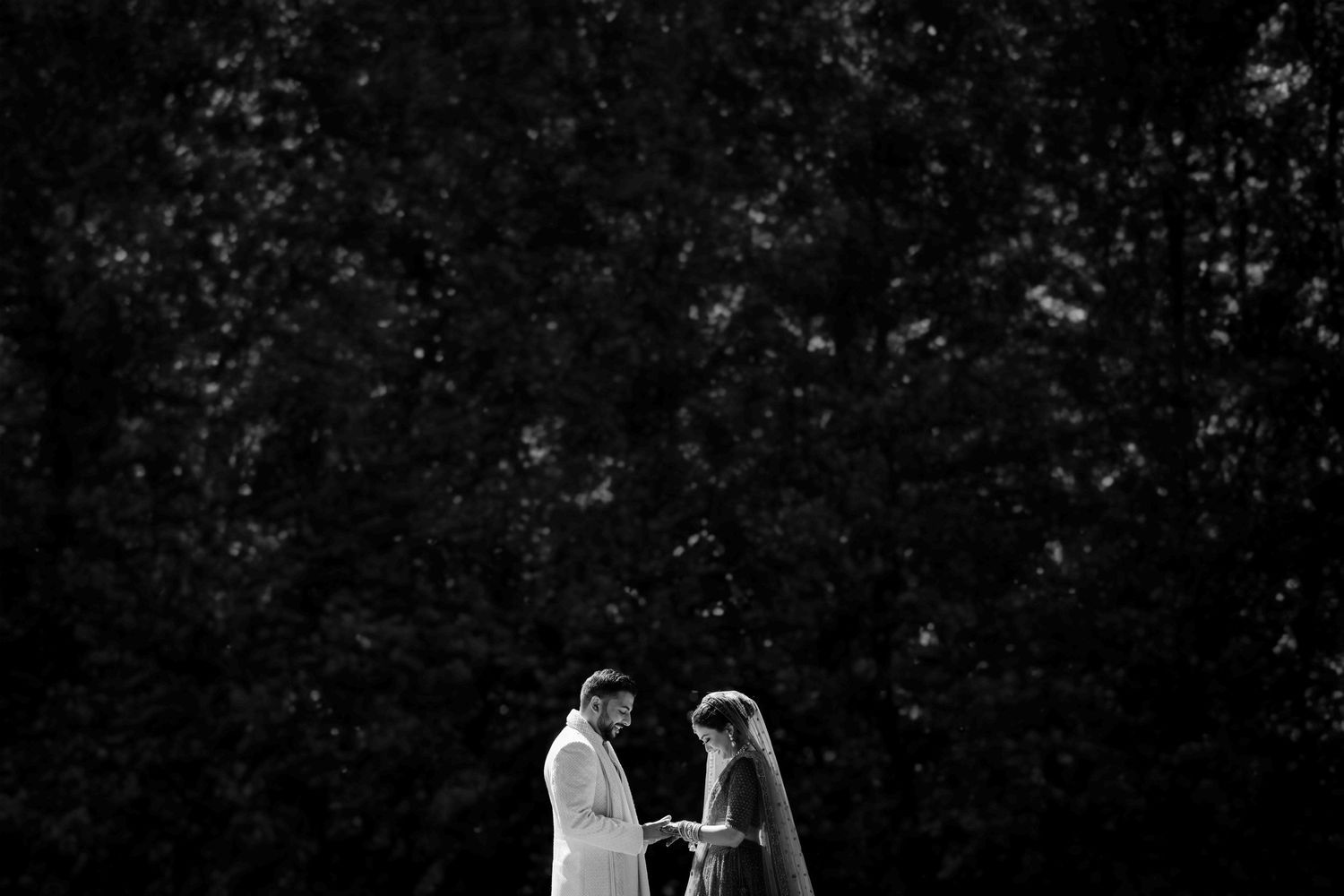 Black and white image of a romantic moment during an outdoor wedding ceremony.