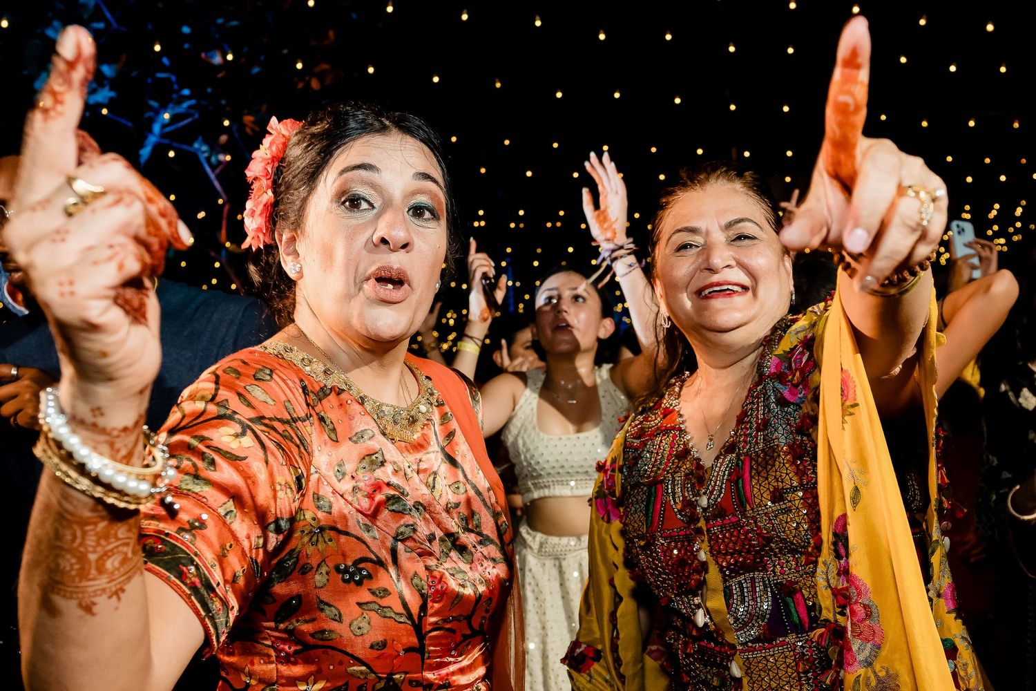 Joyful celebration with dancing and traditional Indian clothing under twinkling lights at a festive event.