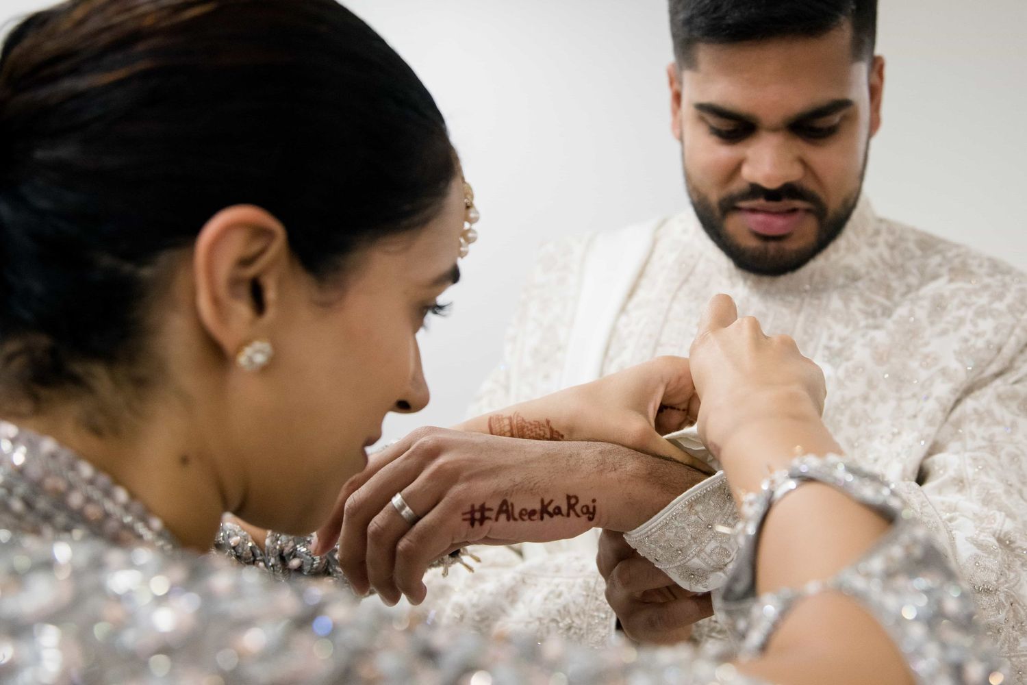 Close-up of hands during traditional Indian wedding ceremony with detailed attire and henna.